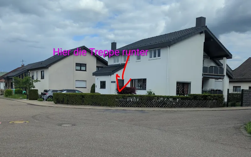 Foto: Straße mit Wohnhaus, ein Pfeil zeigt auf die Treppe zur Fahrschule