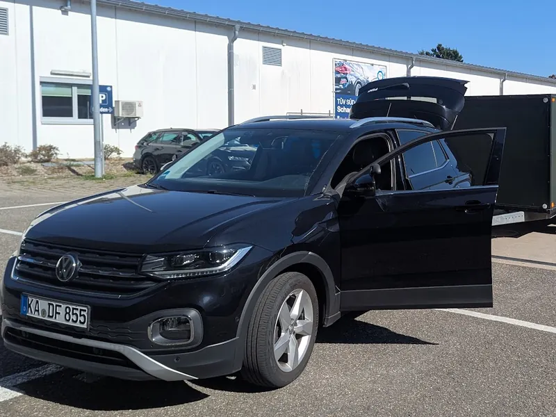 Daniels Fahrschulauto, ein schwarzer VW T-Cross, mit offener Tür auf einem Parkplatz